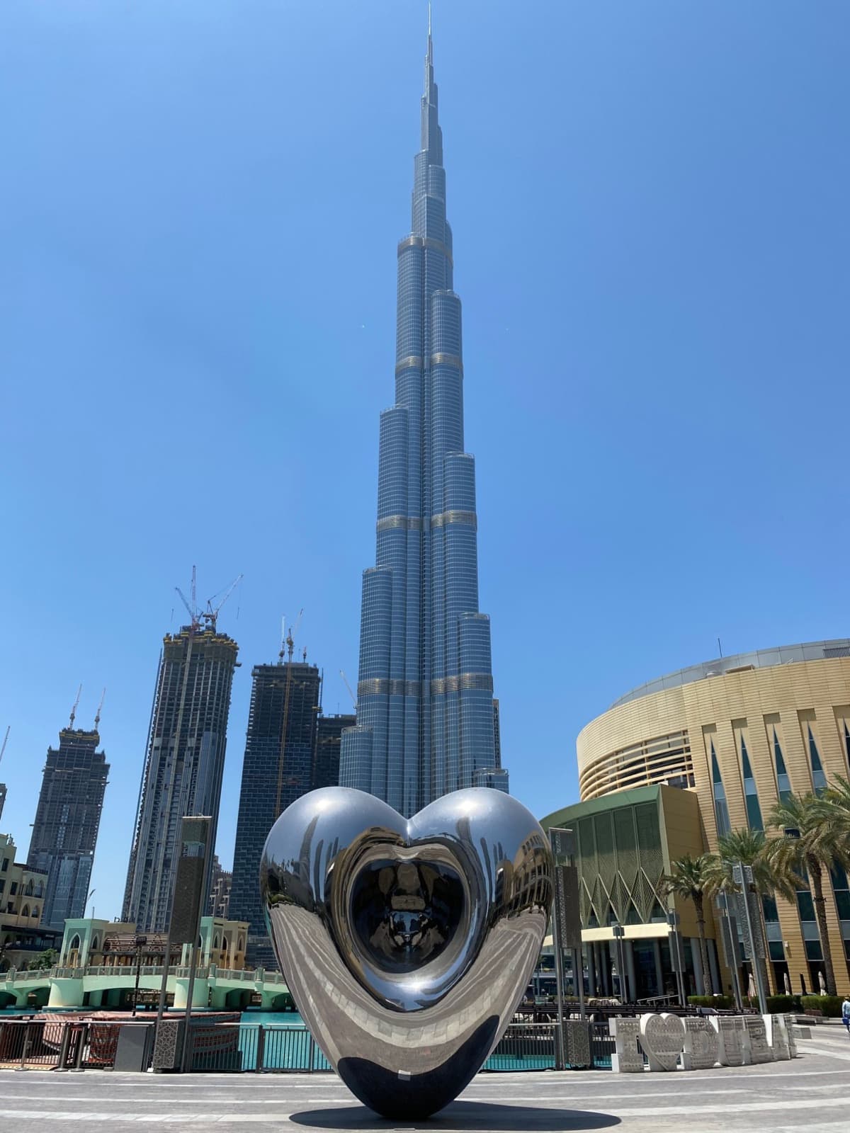 A mirrored heart sculpture in front of the Burj Khalifa