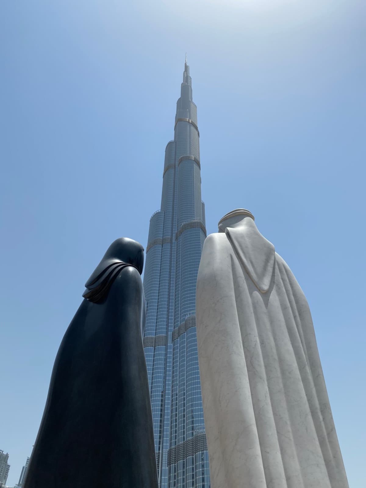 Two sculptures in traditional Emirati dress looking up at the Burj Khalifa